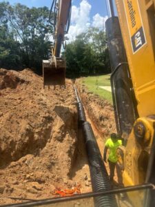 a trench being dug with an excavator by One Stop Dumpsters and Demo in Charlotte North Carolina